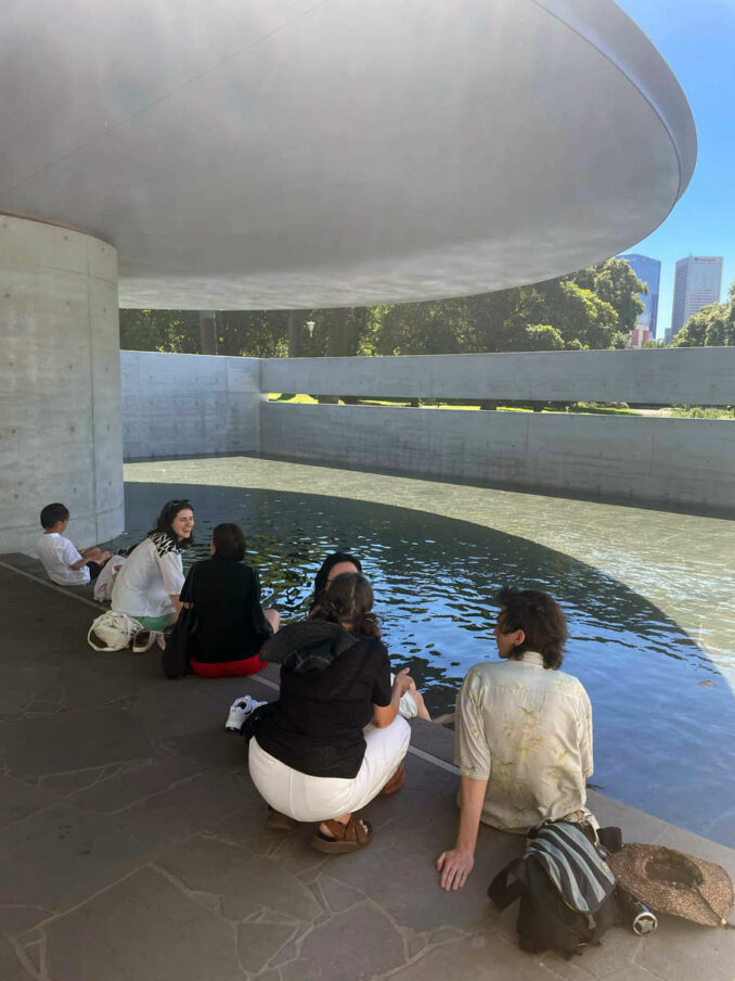 People sitting with their feet in the water at the MPavilion